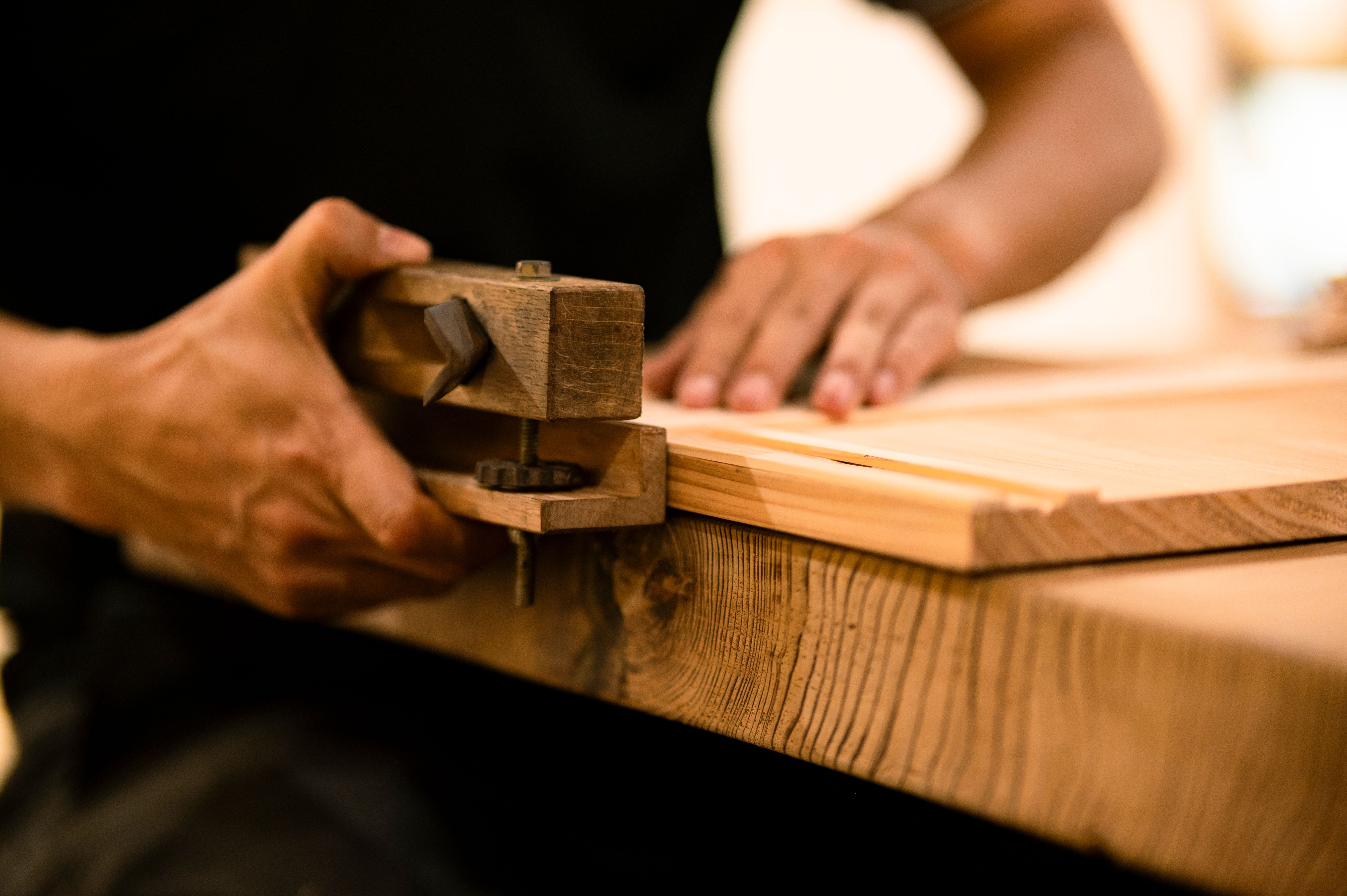 Craftsperson shaping a wooden board with a hand tool